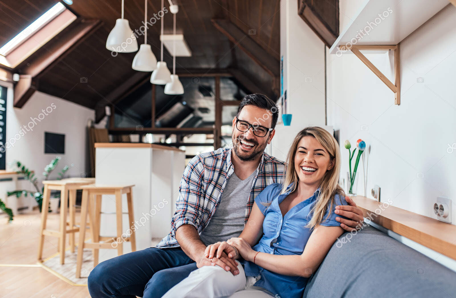 laughing young couple sitting on the sofa at their new modern ap